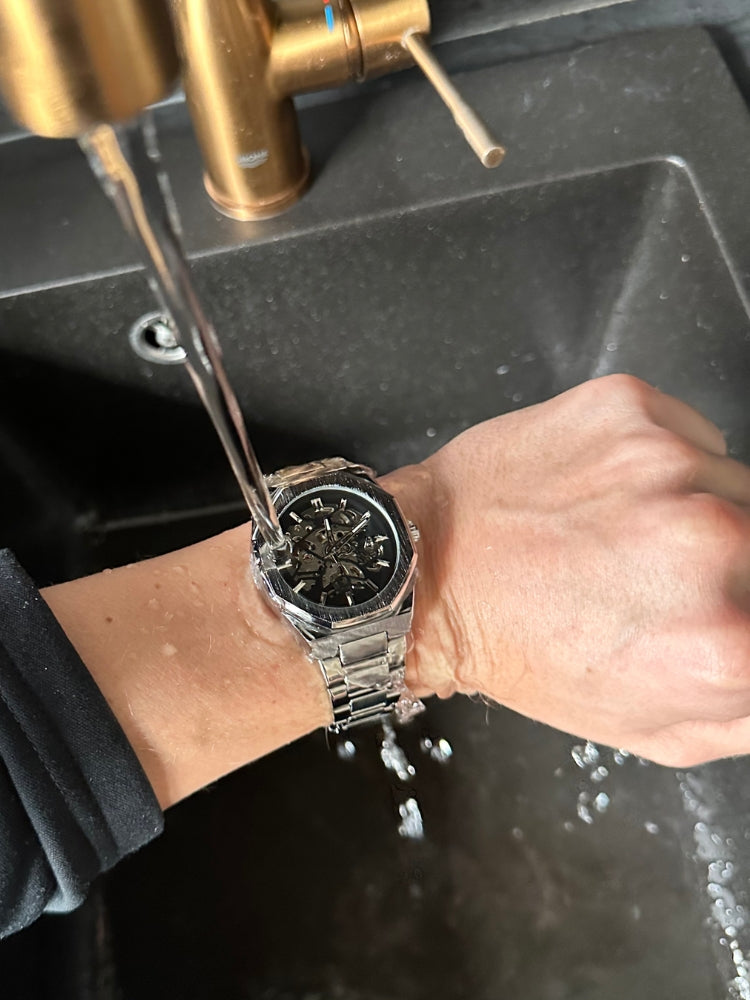 "Modern elegant herenhorloge met roestvrijstalen band, transparante wijzerplaat en open design. Tijdloos en stijlvol accessoi