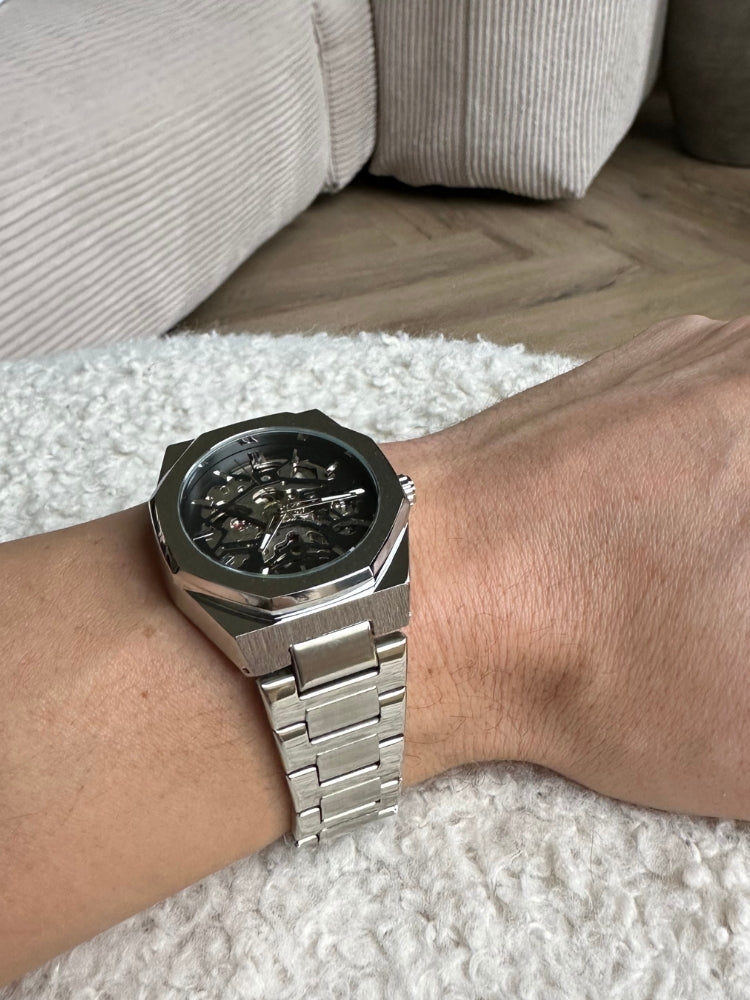 "Modern elegant herenhorloge met roestvrijstalen band, transparante wijzerplaat en open design. Tijdloos en stijlvol accessoi
