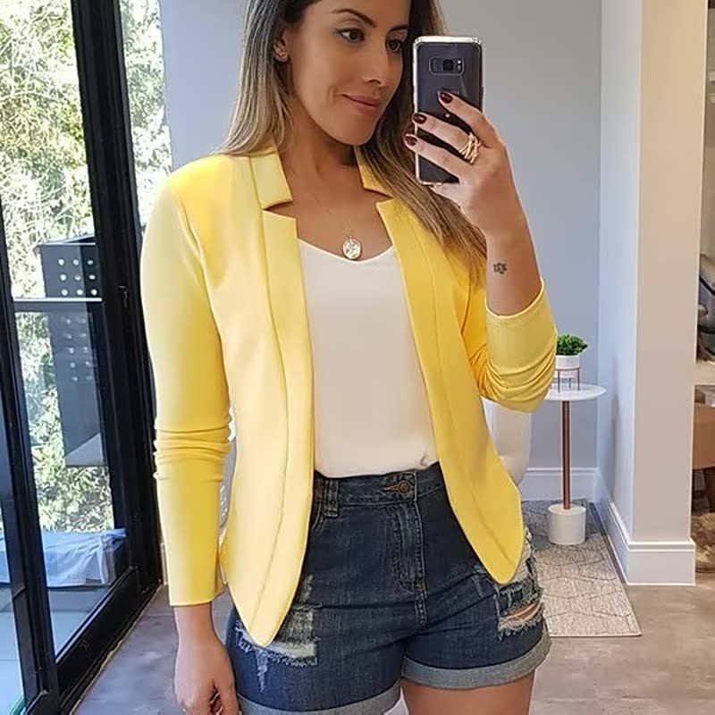 Vrouwelijke model lacht terwijl ze een chique rode blazer draagt over een witte blouse, passend voor kantoor.