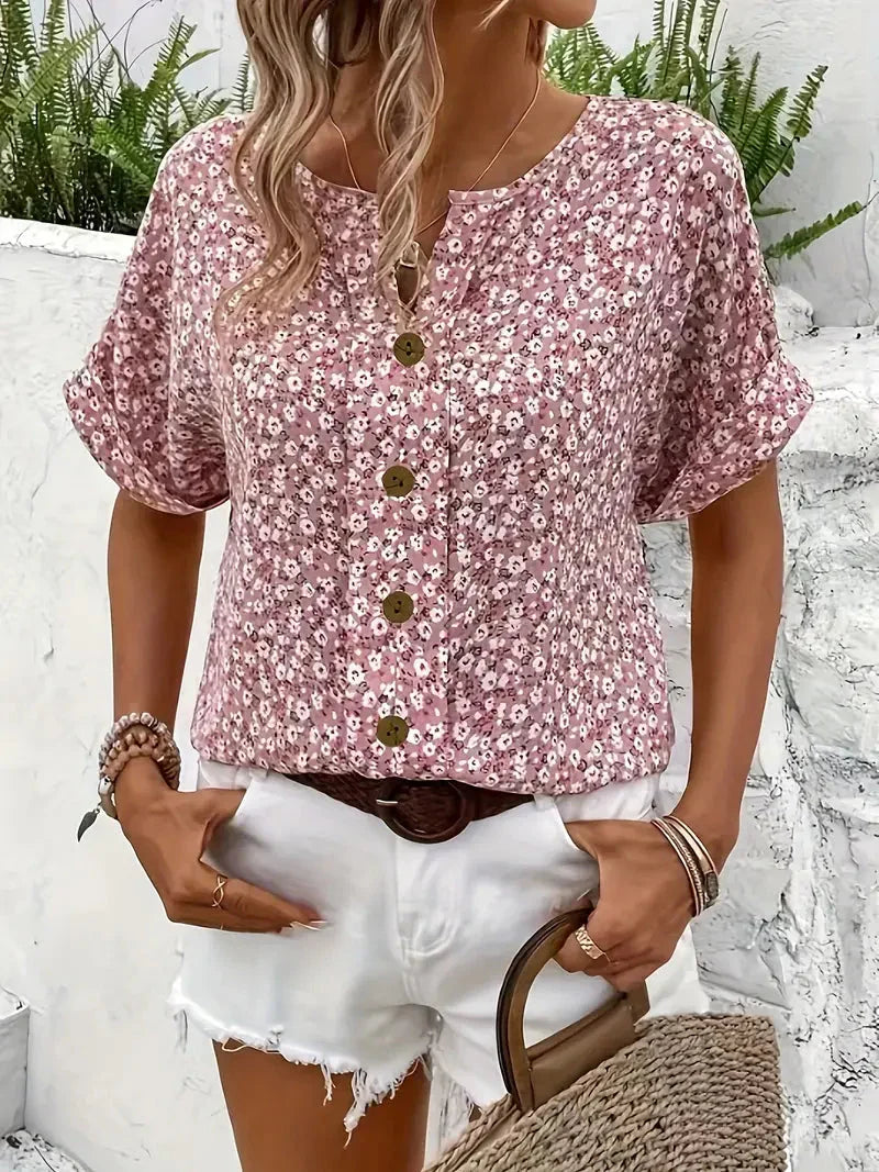Vrouwelijke zomerblouse met bloemenprint, ronde hals en subtiele knoopsluiting, een stijlvolle roze top.