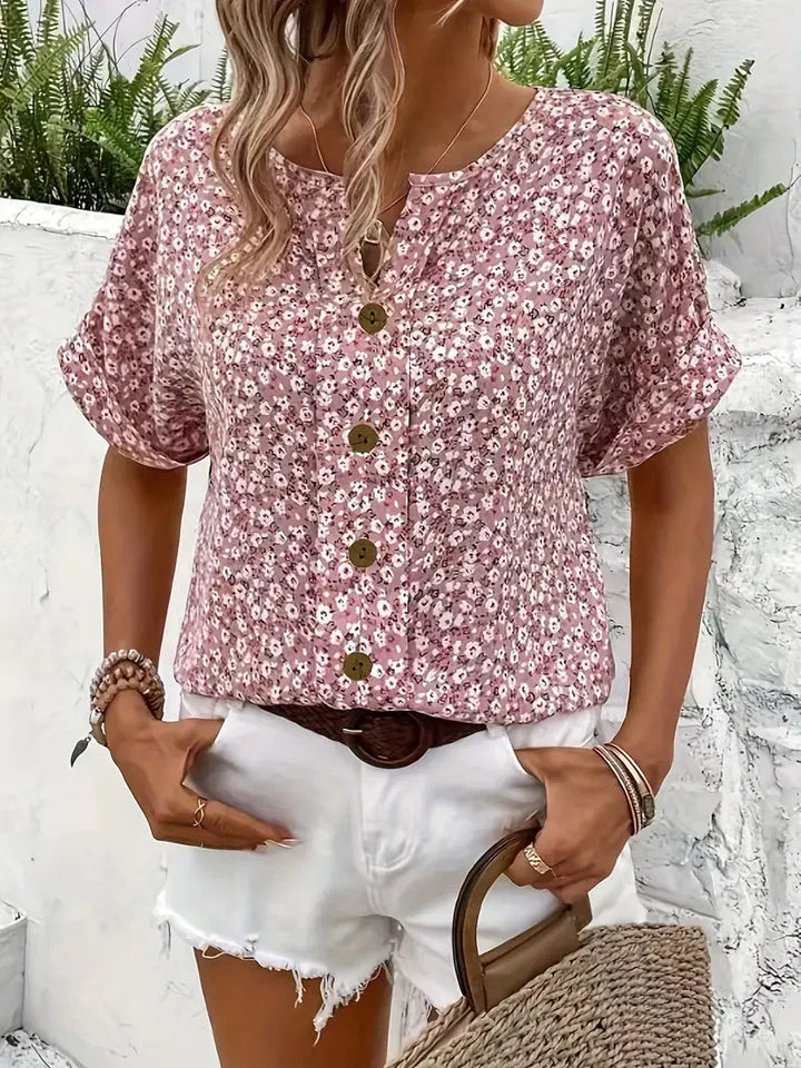 Vrouwelijke zomerblouse met bloemenprint, ronde hals en subtiele knoopsluiting, een stijlvolle roze top.
