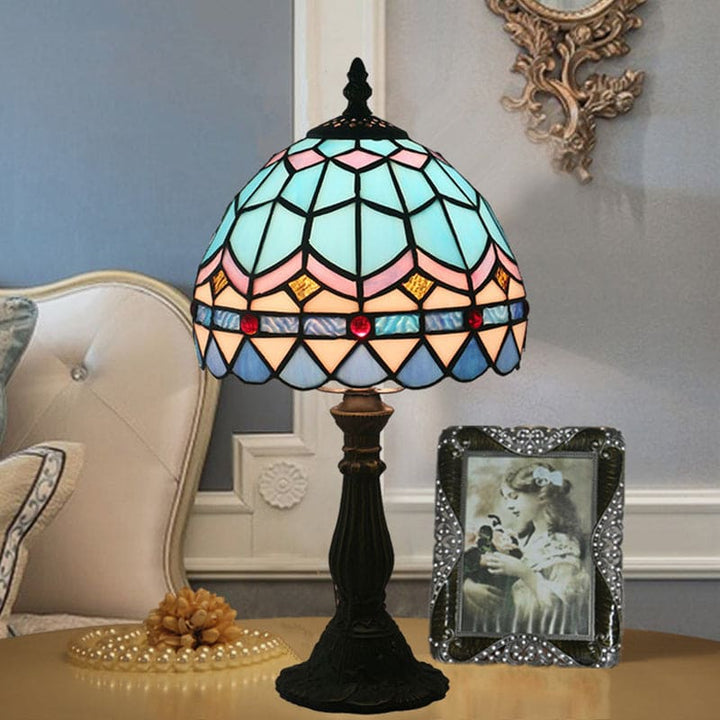 "Tiffany-stijl tafellamp, blauw en geel glas, klassieke loodlijnen, warme en uitnodigende sfeer, ambachtelijk design."
