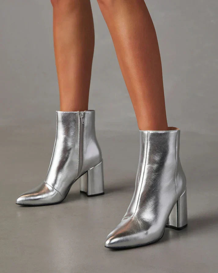 Zilveren metallic enkellaars met glamour blokhak, puntige neus en ritssluiting. Verhoog je stijl met deze elegante laarsjes.