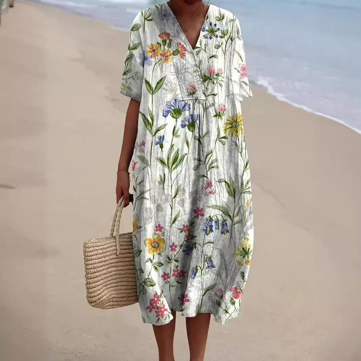 Zomerjurk Tess met bloemenprint, luchtige midi dress in kleurrijke bloemen, ideaal voor zonnige dagen met elegant design.